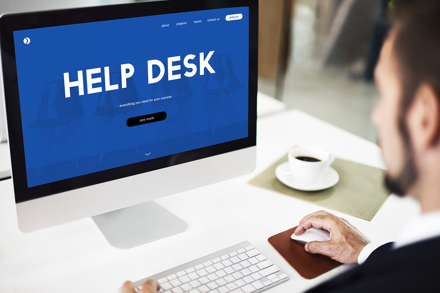 schermo di computer MAC con sfondo blu e scritta help desk con uomo che guarda